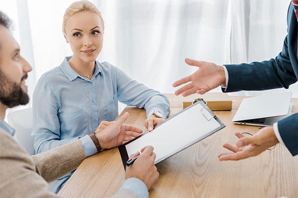 couple signing documents on clipboard